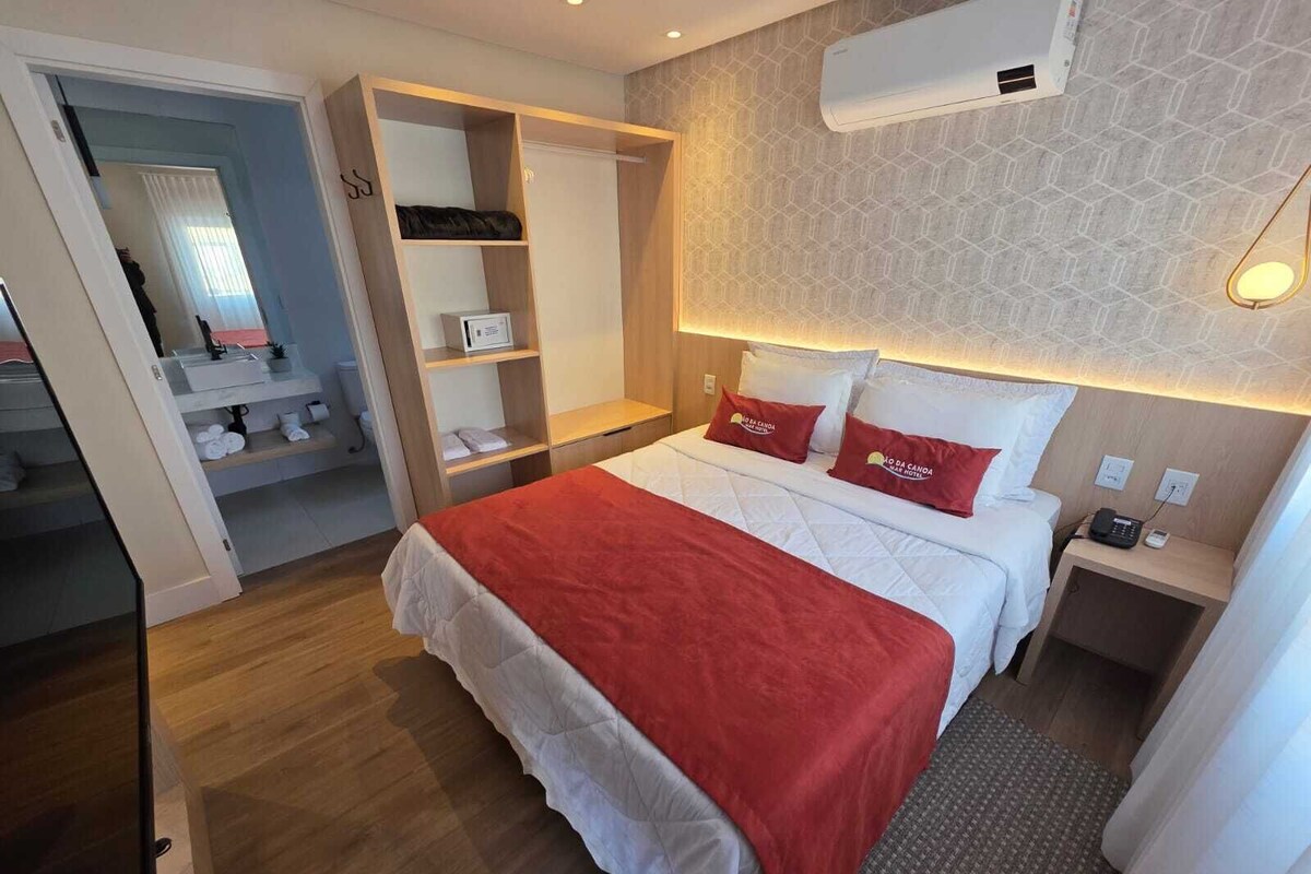 Une chambre d’hôtel équipée d’un lit, d’une armoire, d’une table de chevet et d’un climatiseur fixé au mur.