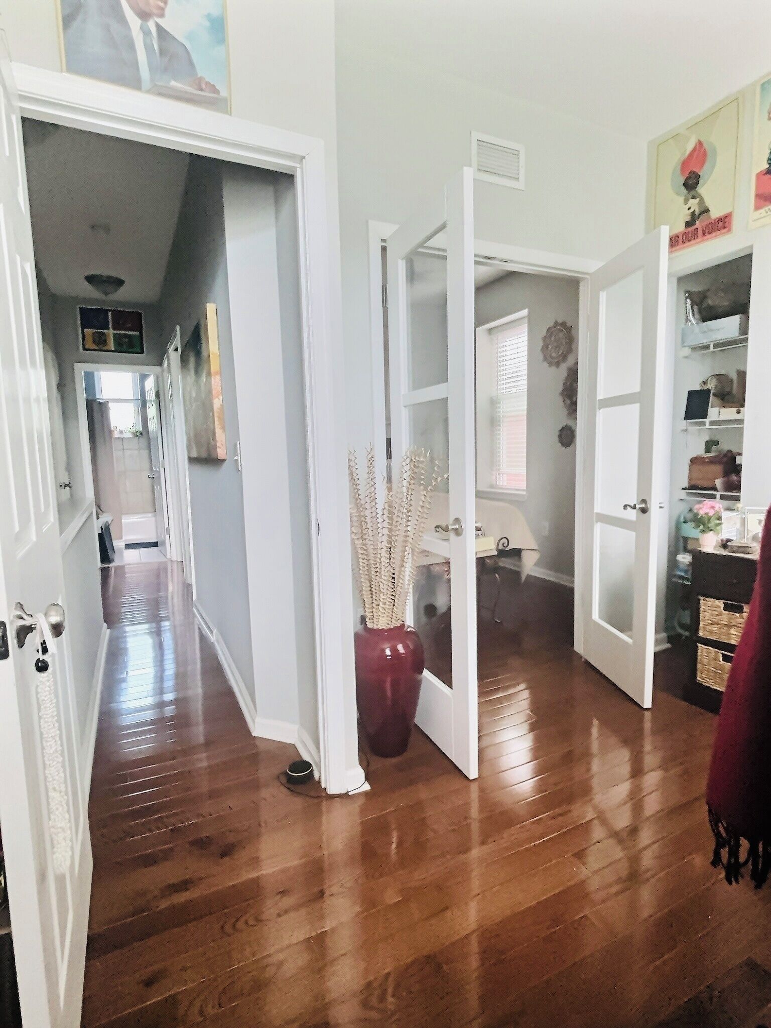 A hallway with open doors leading to various rooms, a wooden floor, and a potted plant.