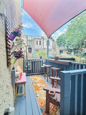 A covered outdoor patio with wooden furniture and potted plants.