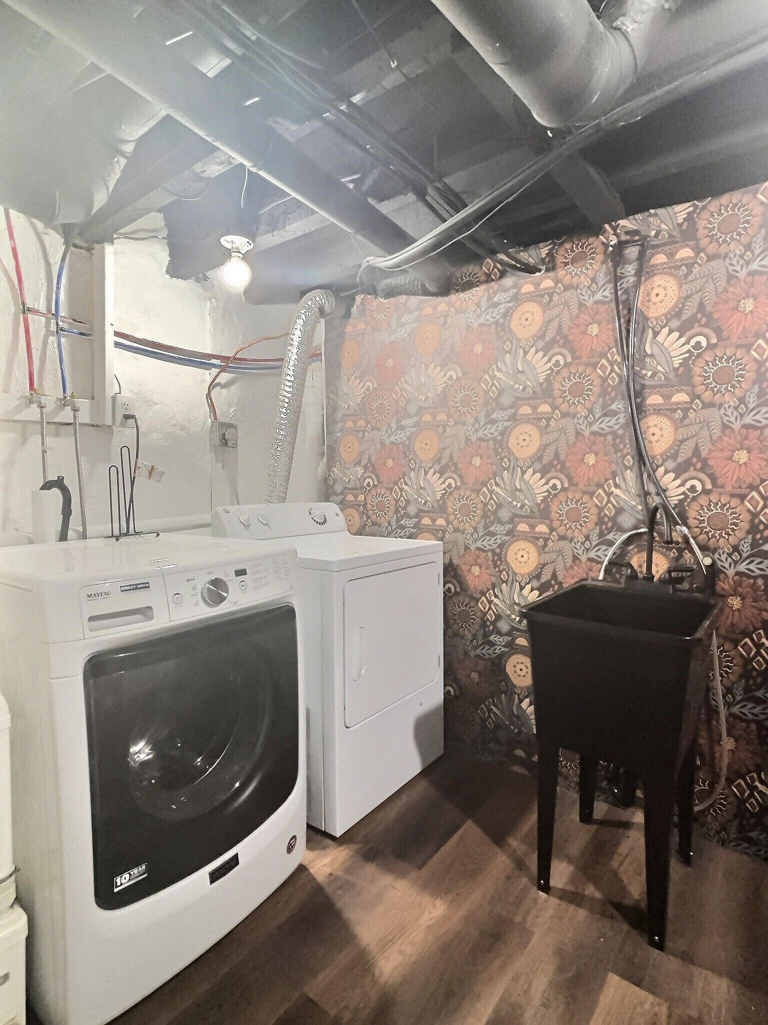 Een wasserette met een wasmachine, droger en een stoel.