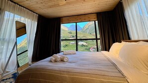 A room with a large bed, a window with a mountain view, wooden ceiling, and sheer curtains. - Gorgeous 1-bedroom cabin in peaceful Juta for a cozy escape (Juta)