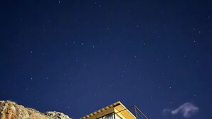 A wooden cabin with a balcony, set against a rocky hillside under a starry night sky. - Gorgeous 1-bedroom cabin in peaceful Juta for a cozy escape (Juta)