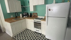 Een keuken met witte kasten, een fornuis, een koelkast en een vloer met een patroon.
