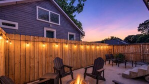 Un jardin avec une clôture en bois, un espace salon extérieur et un foyer.