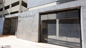 A building with a closed shutter, a sign reading 'ED. SAN JUDA'S', and a visible entrance.