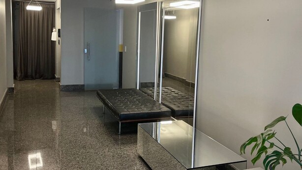 A modern hotel room with a large mirror, a sofa, a small table, and a plant.