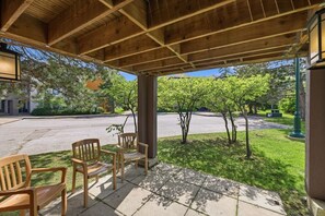 A covered outdoor seating area with wooden chairs and a view of a street and trees. - Village Side 3BDR | New Kitchen & Private Patio (The Blue Mountains)