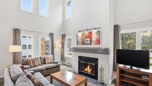 Una sala de estar amplia con chimenea, televisor y un ventanal grande.