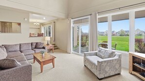 A spacious living room with a large window, a sofa, a coffee table, and a fireplace. - Ground-Floor Home with Sauna on Monterra Golf (The Blue Mountains)