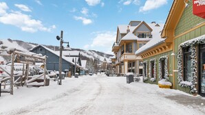 A snow-covered street with buildings, including a warming center and a hotel with a snow-covered entrance. - Ground-Floor Home with Sauna on Monterra Golf (The Blue Mountains)