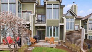 Un edificio residencial de varios pisos con un patio cubierto, mobiliario exterior y un pequeño jardín.