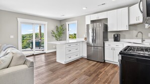 Una cocina moderna con armarios blancos, un refrigerador de acero inoxidable y una estufa negra.