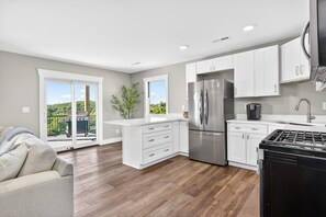 Une cuisine moderne avec des meubles blancs, un réfrigérateur en acier inoxydable et une cuisinière noire.