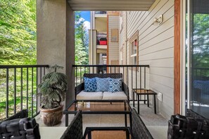 A balcony with a sofa, a potted plant, and a small table.