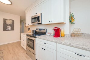 A modern kitchen with white cabinets, stainless steel appliances, and a granite countertop.
