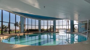 Una piscina interna con ampie finestre, una panca e una cascata.