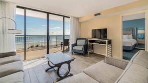 Una camera d'albergo con balcone, TV, un letto e un’area salotto.