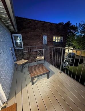 A wooden deck with a metal railing, a bench, and two chairs. - Colours of 4927- 2 bedrooms-Queen size- one free parking (Niagara Falls)