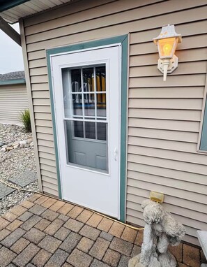A house with a white door, a window with a grid pattern, and a wall-mounted light fixture.