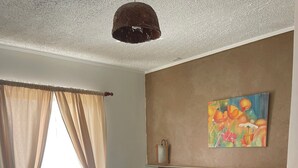 Un dormitorio con cama, cortinas, un cuadro y una lámpara.