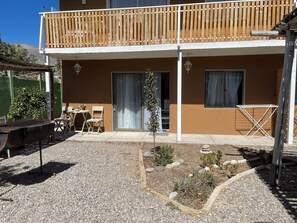 A two-story building with a balcony, a small garden area with plants and rocks, and a table with chairs outside. - Rancho Elquino (Vicuña)