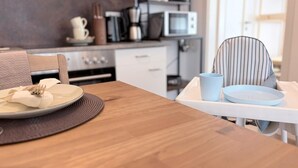 Un comedor con una mesa de madera, una silla y una trona.