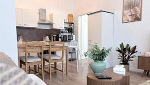 Una sala de estar moderna con comedor, una cocina al fondo y un ventanal grande.
