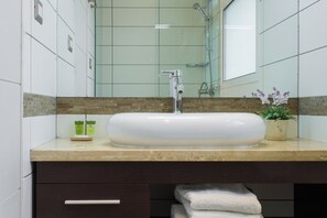 A bathroom with a large white sink, a mirror, and a shower. There are towels and a potted plant on the counter. - Beautiful superior duplex apartment (Santiago)