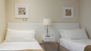 A hotel room with two beds, a nightstand with a lamp, and two framed pictures on the wall. - Beautiful superior duplex apartment (Santiago)