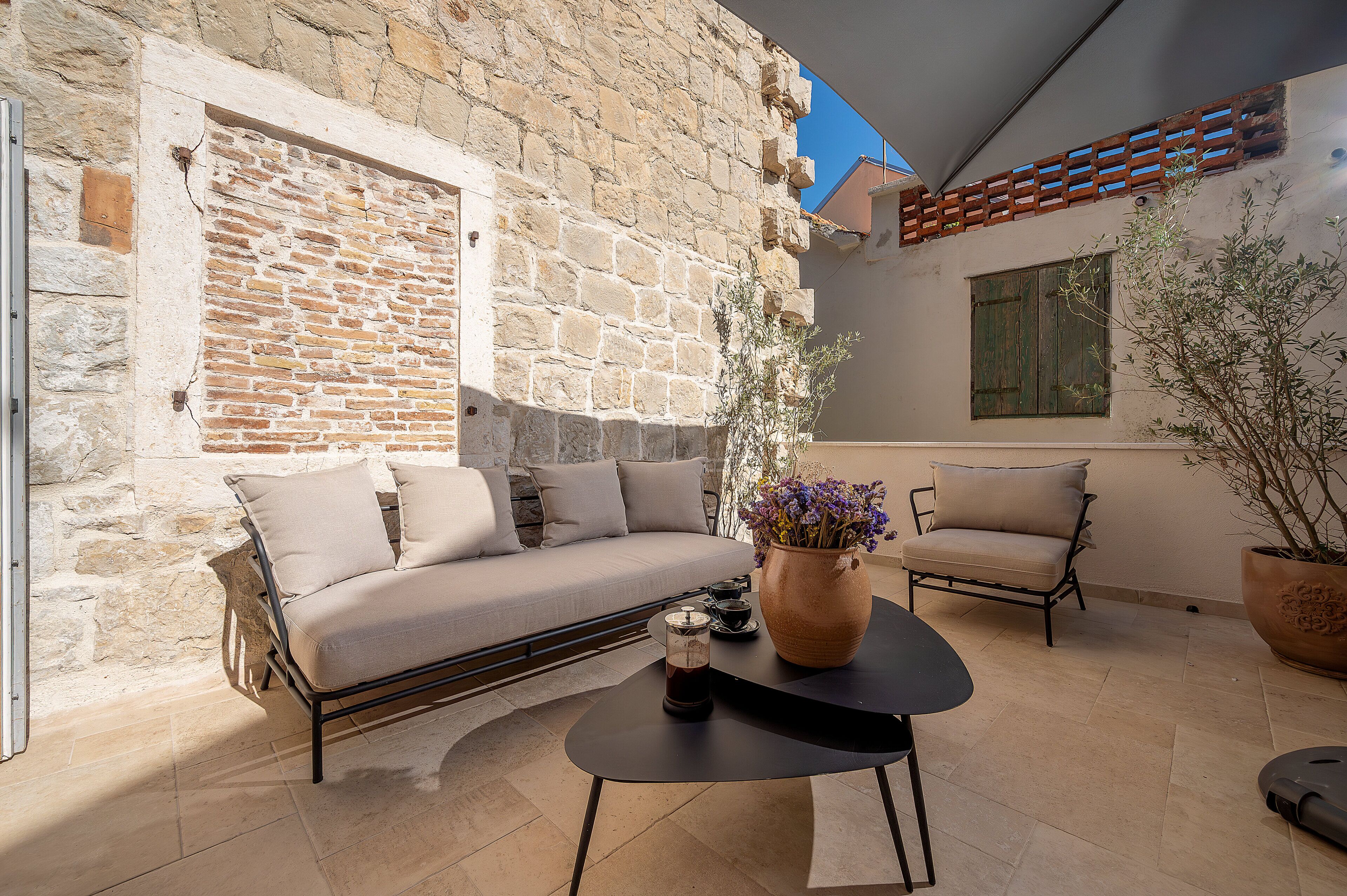 A stone-walled room with a sofa, a table with a candle, and a potted plant.