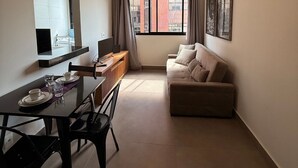 A modern living room with a dining area, a sofa, a TV, and a window with curtains. - LK Santa Efigênia 1 (Belo Horizonte)