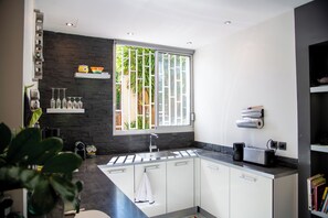 Eine moderne Küche mit Steinrückwand, einem großen Fenster und einem integriertem Toaster.