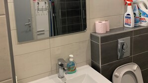 Een badkamer met een wit wastafel, een spiegel, een douchecabine en toiletartikelen op het aanrecht.