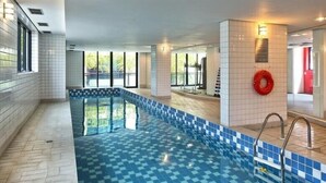 Una piscina con bordes azulejados, un flotador salvavidas y vistas al exterior.