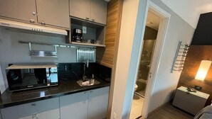 Una cocina moderna con armarios grises, encimera negra, cafetera y microondas integrado.