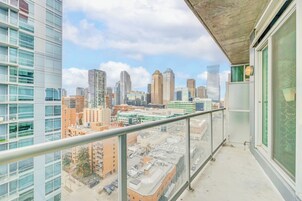 Un balcon offrant une vue sur le paysage urbain, avec de modernes gratte-ciel et un ciel dégagé.