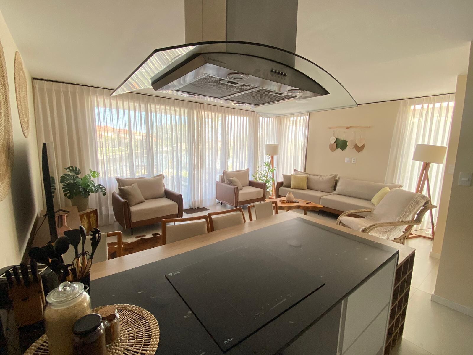 A modern living room with a kitchen area, featuring a large island, sofas, and a dining table.