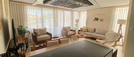 A modern living room with a kitchen area, featuring a large island, sofas, and a dining table.