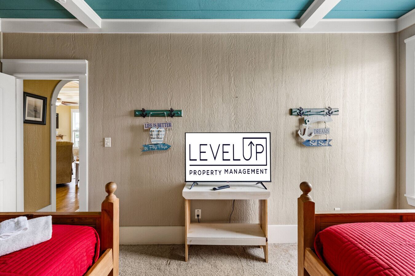 A bedroom with two wooden beds, a small table, and a sign for 'LEVELUP PROPERTY MANAGEMENT' on the wall.