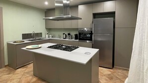 A modern kitchen with a central island, stainless steel appliances, and a tiled floor.