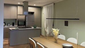 A modern kitchen with an island, dining area with chairs, and a view of the living space.