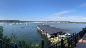 Blick auf das Wasser mit Booten, einem überdachten Steg und einer Terrasse mit Sitzgelegenheiten.