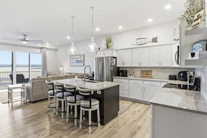 Una cocina moderna con una isla central, muebles blancos y vistas al exterior.