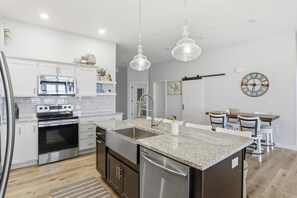 A modern kitchen with white cabinets, stainless steel appliances, a granite countertop, and pendant lighting. - Luxury 3b 2ba sleeps 8 (Osage Beach)