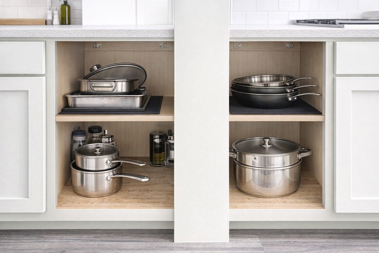 A kitchen with stainless steel cookware, including pots and pans, on open shelves.