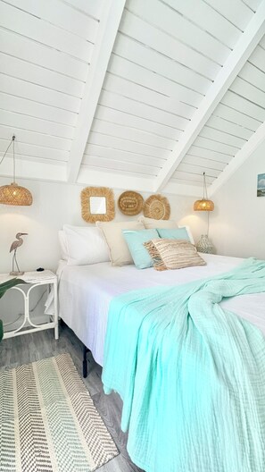 A bedroom with a bed, bedside tables, and wall decorations. - Steps to Beach, Eats, ATM, Taxi, Pool View, Golf and Grocery store (Frigate Bay)