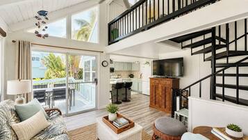 A spacious living area with a balcony, a kitchen, and a staircase.