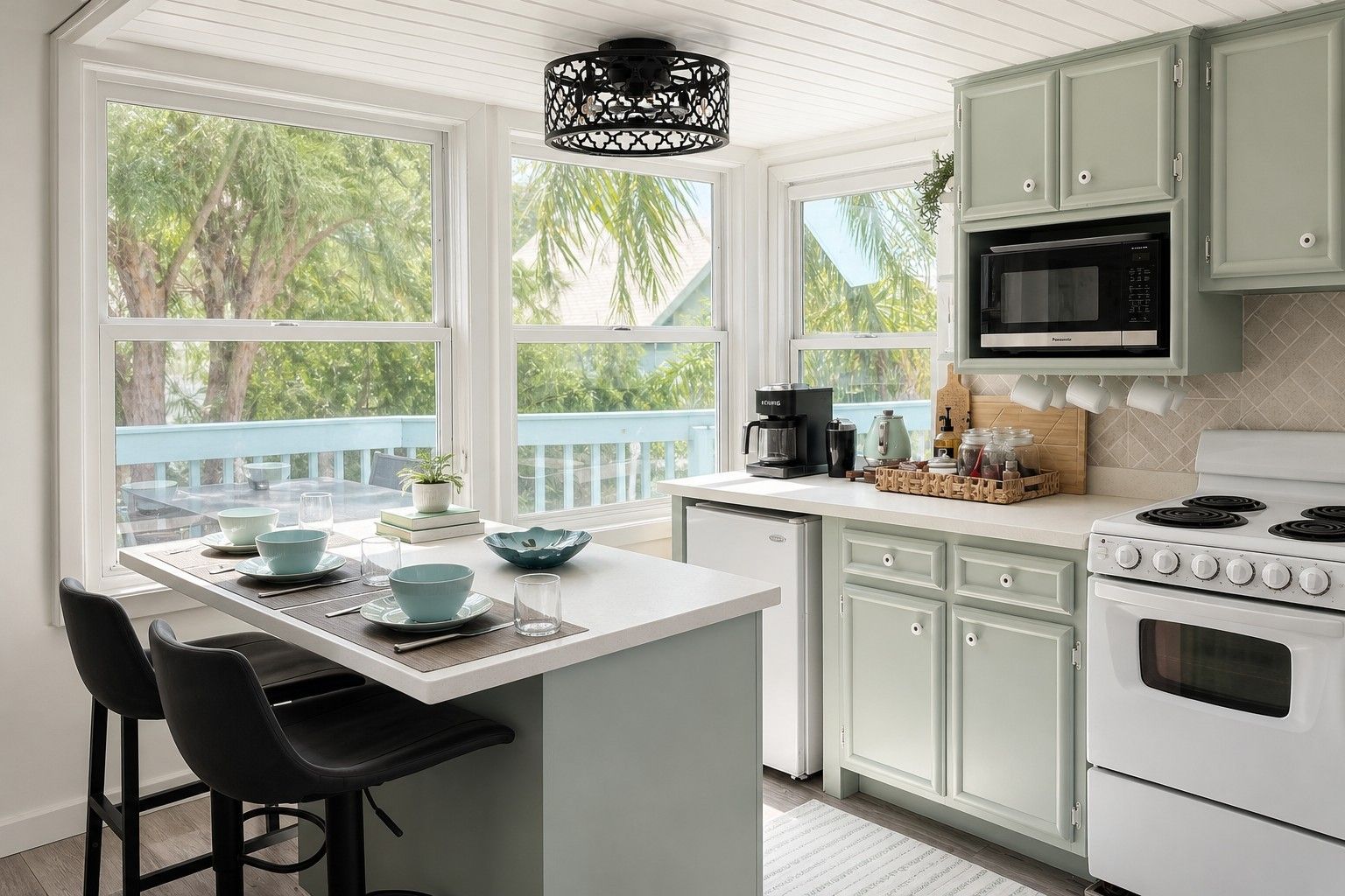 A kitchen with a central island, white cabinets, a microwave, and a stove.