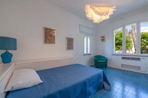 A room with a bed, a chair, a window, and artwork on the walls. - Villa Vesuvius Skyview With Amazing Pool & Terrace (Sorrento)