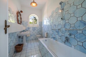 Une salle de bain avec un lavabo, des toilettes et une baignoire, le tout agrémenté de motifs hexagonaux sur les carreaux.